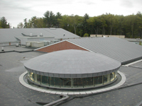 A new membrane roof on a round drum shaped building next to a larger low slope roof