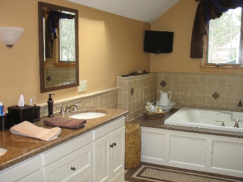 Bathroom with a granite topped vanity and a tiled tub deck