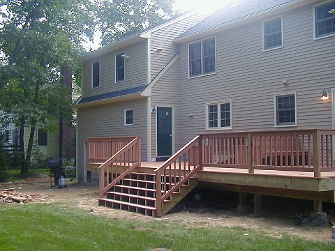 Rear elevation of a house with a new deck and stairs down to the lawn