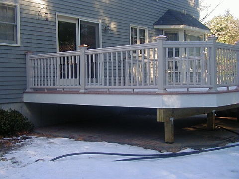 Raised deck with white rail and stairs at the back of a house