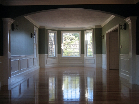 Formal room with square columns, painted wainscot and polished hardwood floors