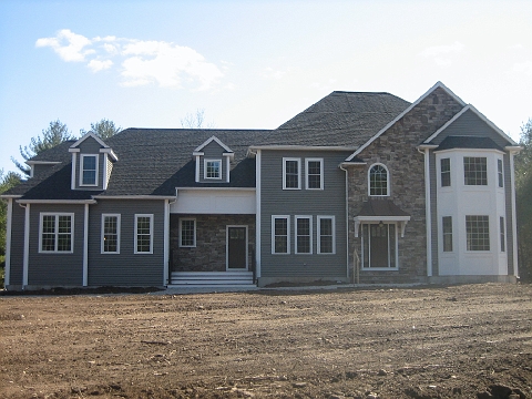 The same new home seen from the front, lap siding with stone accents, on a raw lot