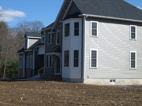 New house with stone accents and a bay window, on a lot not yet graded