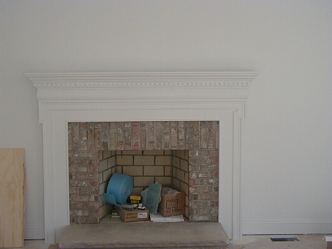 Brick fireplace surround with a painted mantel and dentil moulding