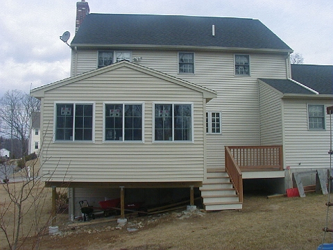Rear elevation of a house with a three season room addition and deck