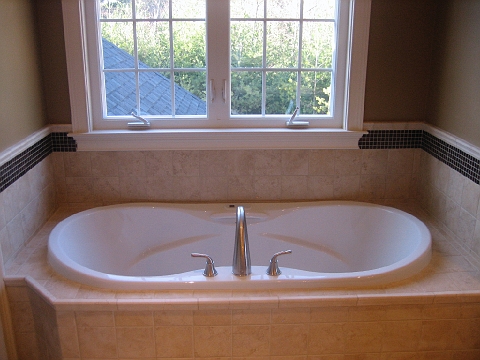 Oval soaking tub set into a tiled window bay