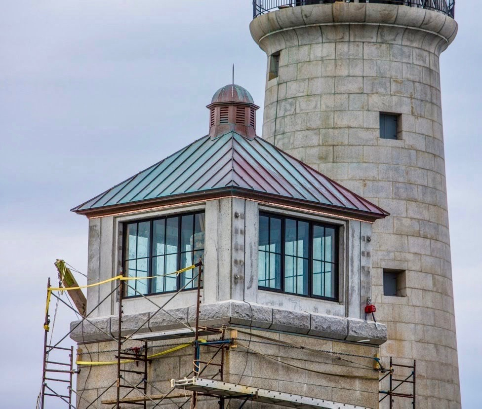 A stone lighthouse tower with a new standing seam copper roof on the lantern