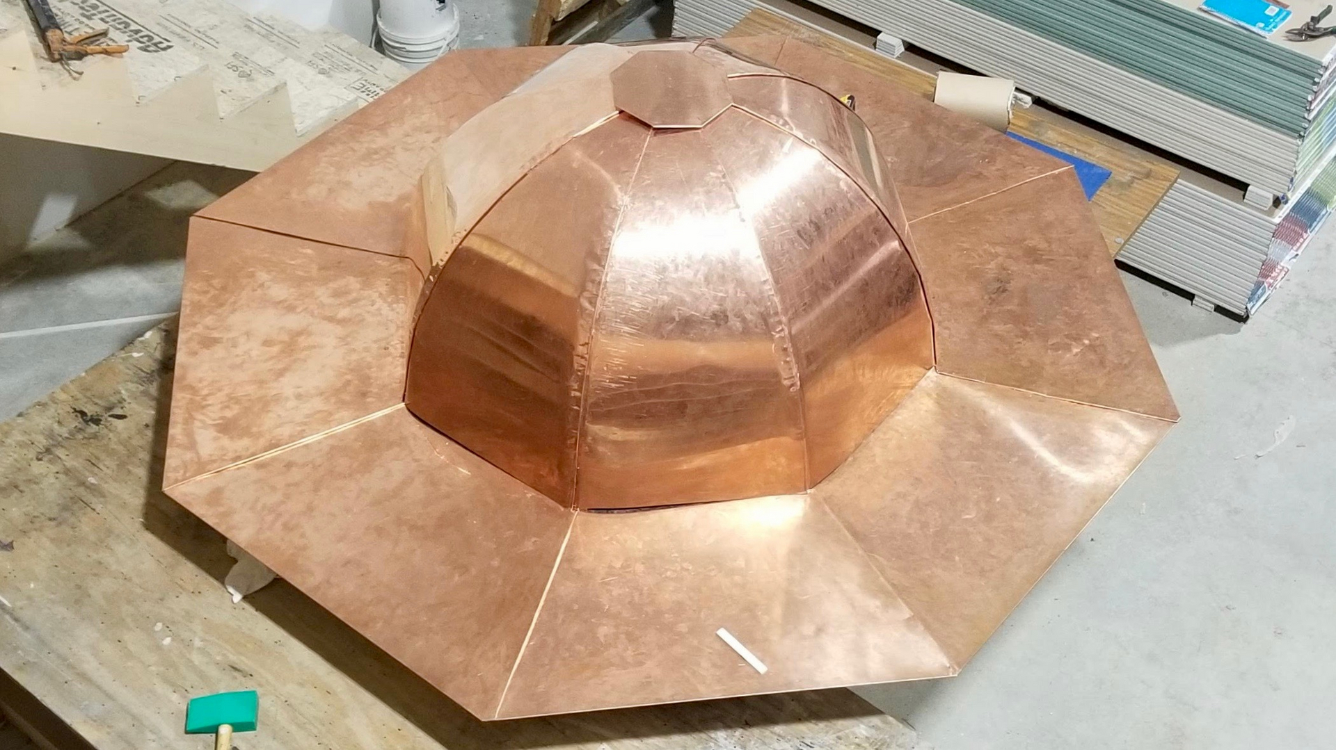A hand formed faceted copper dome sitting on the shop bench