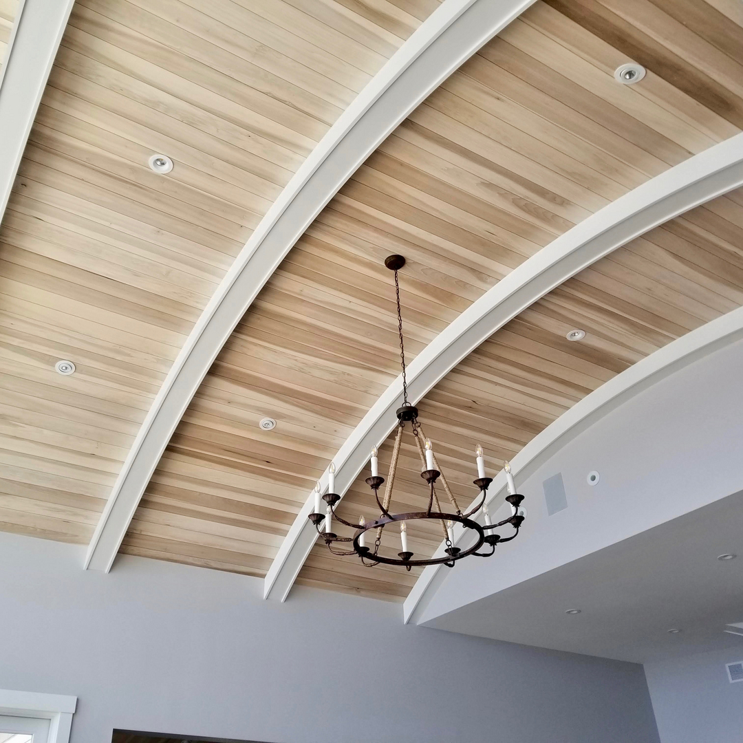 A barrel vaulted ceiling in slatted wood with white ribs and a wrought chandelier