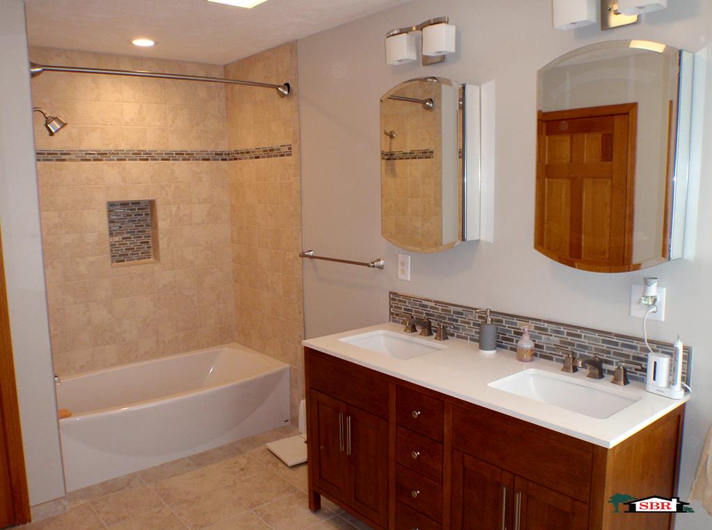 Bathroom with tiled tub surround, glass mosaic band and a double vanity
