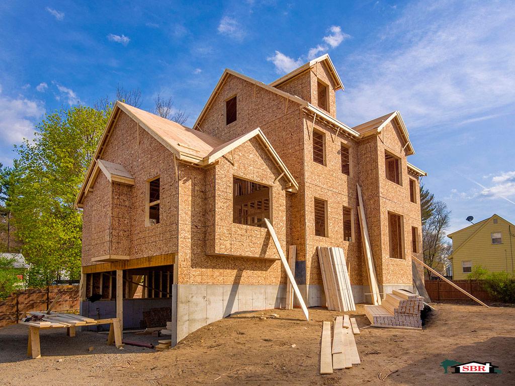 Custom home framed and sheathed under a blue sky