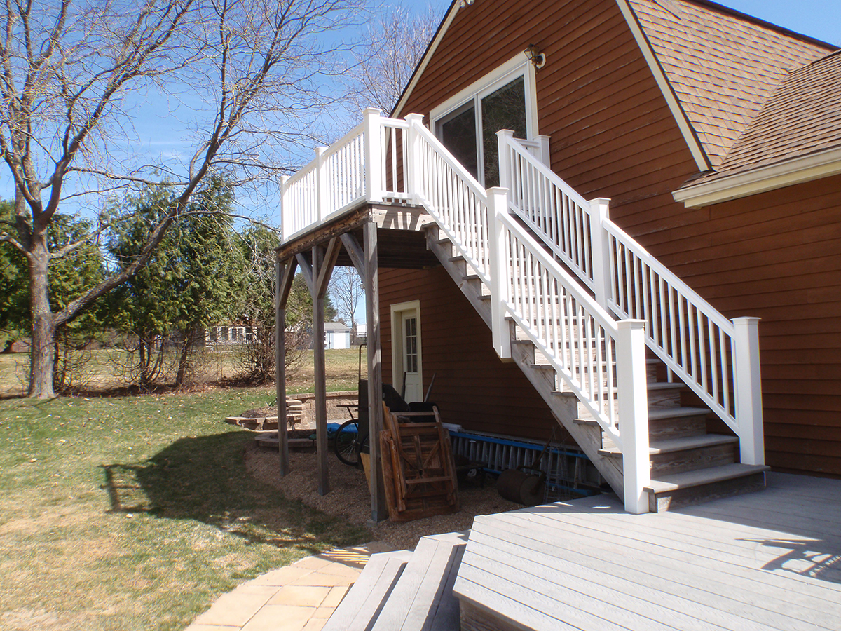 New deck stairs with white rails on a red house