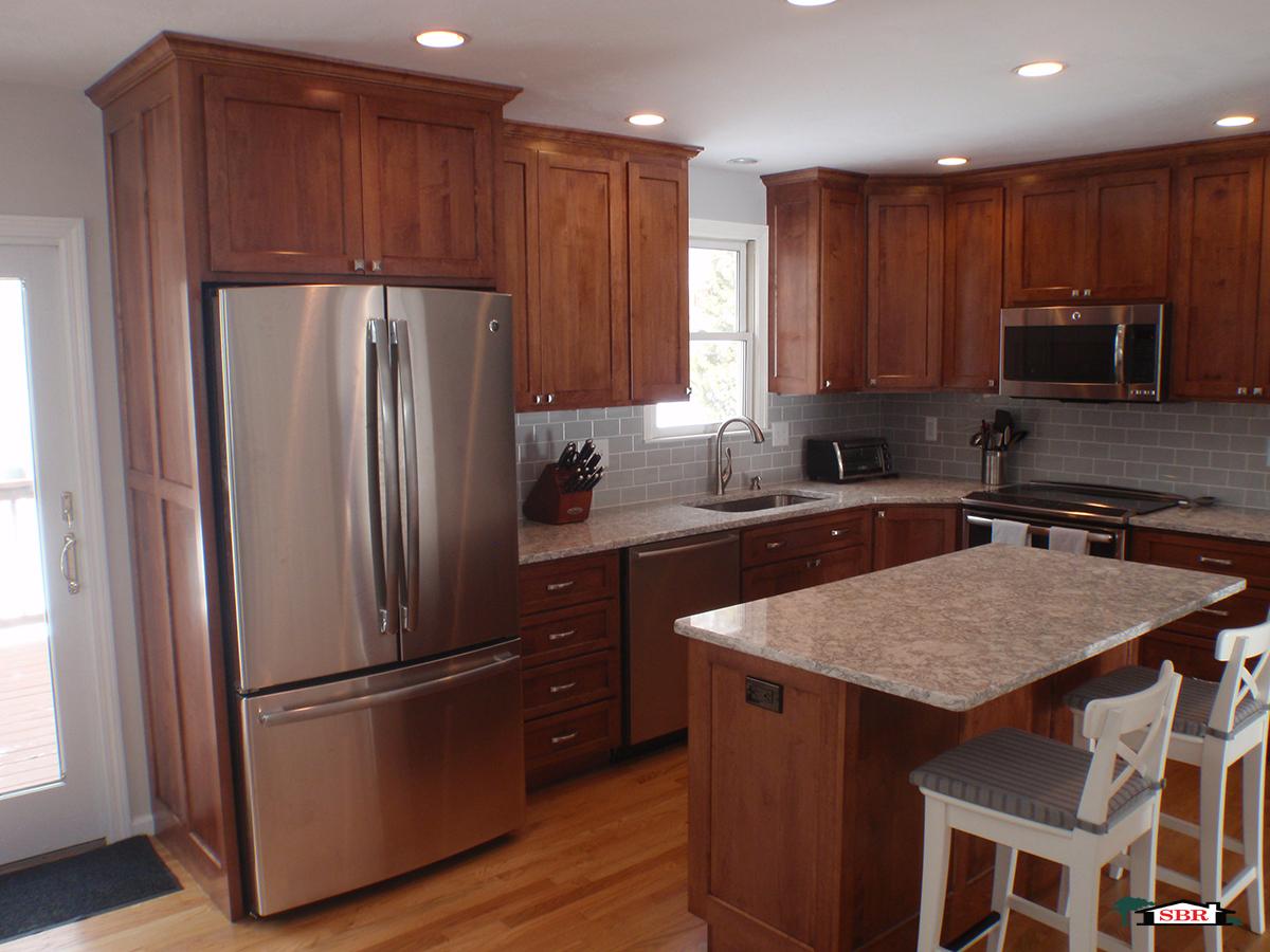 Kitchen with cherry shaker cabinets, gray subway tile and a granite island