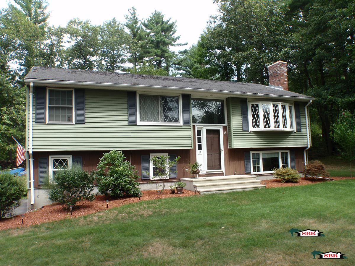 The raised ranch before: green siding, dark shutters and a worn roof