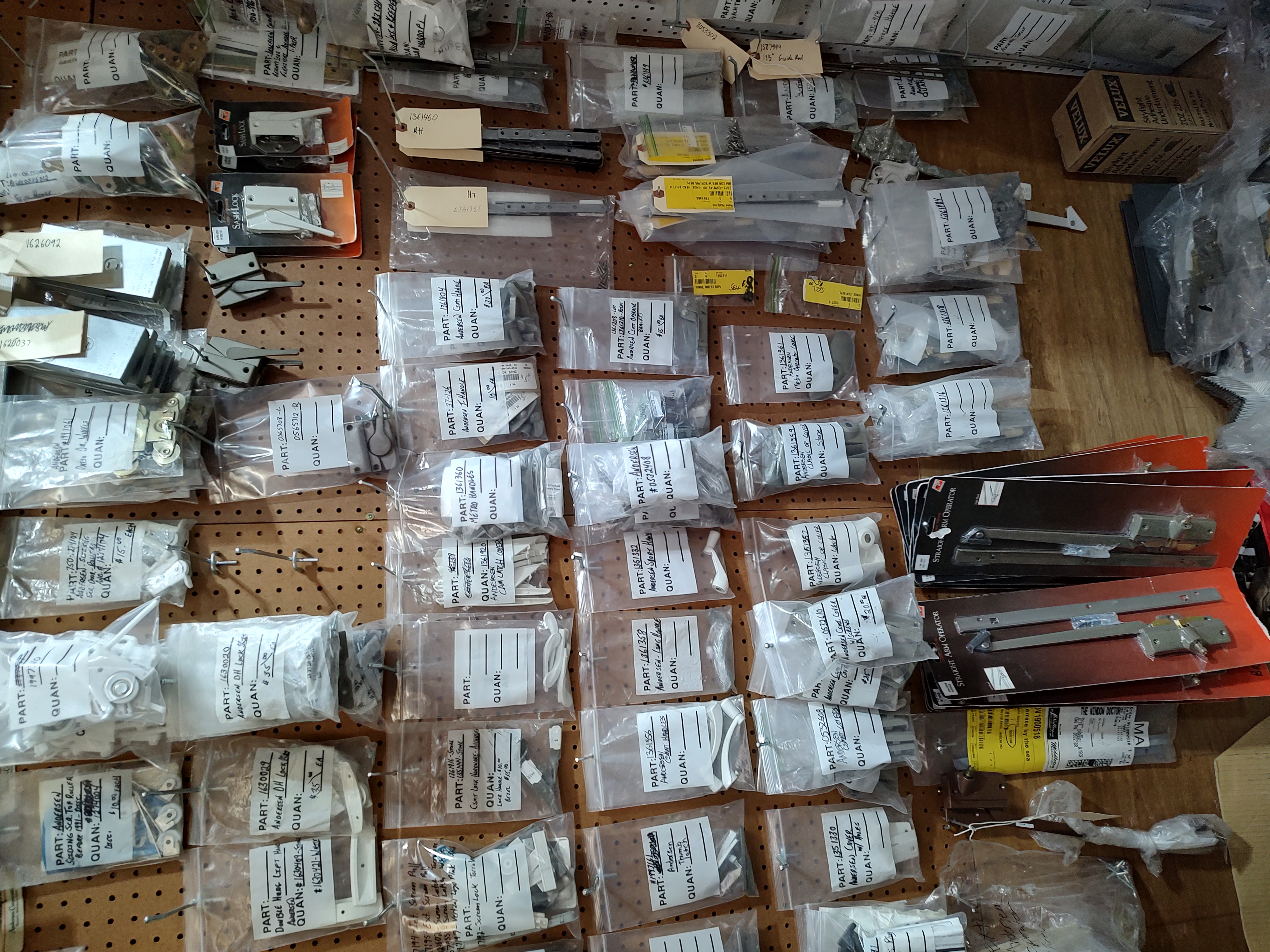 A pegboard wall hung with hundreds of bagged and labeled window and door parts