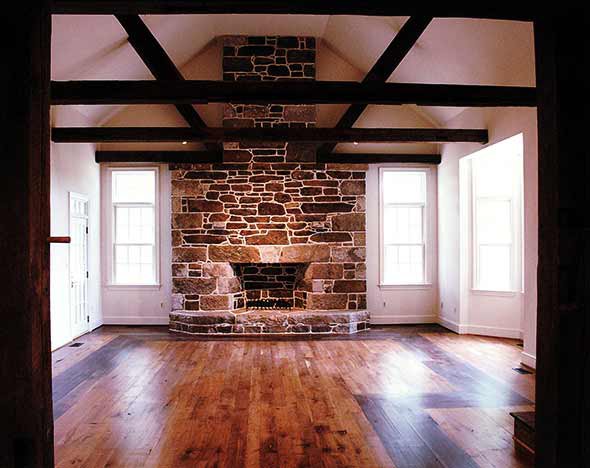 Finished room with exposed beams, a stone fireplace and wide plank floors