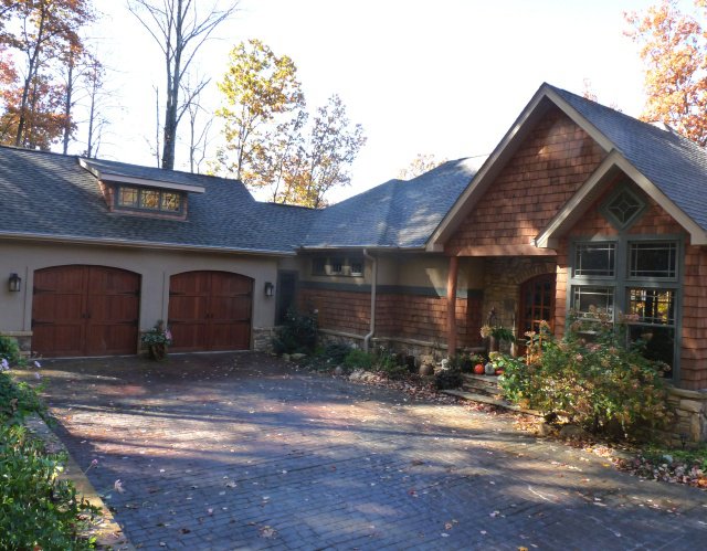 Shingled home exterior with two wood garage doors and a paved drive