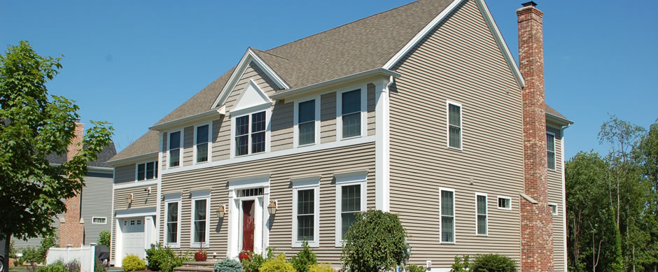 Cream clapboard siding running past a brick chimney on a two story Connecticut house