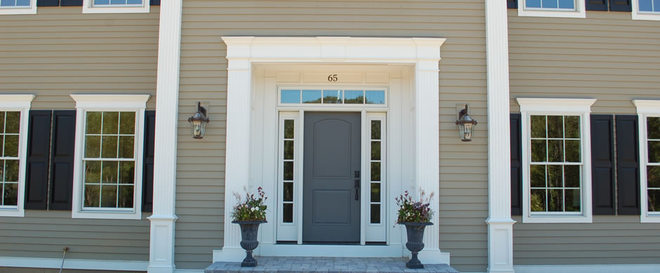 Front door with sidelights and planters set into gray siding