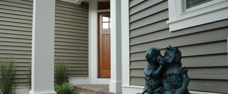 Sage green siding beside a wood front door