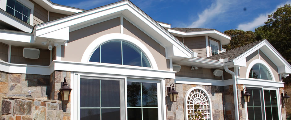 Arched gable window and tall front windows on a beige shingled house