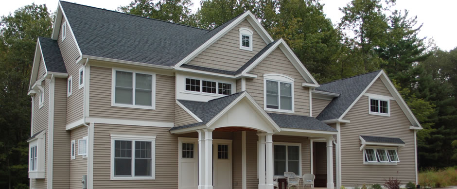 Taupe colonial with a columned portico, dormers and a shake gable