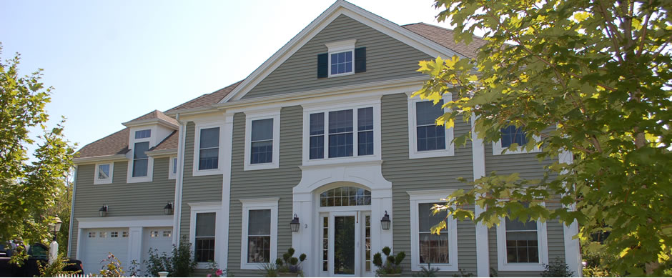 Gray colonial with white trim and a portico, framed by fall foliage