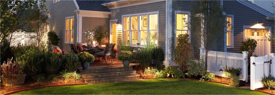 New England home glowing at dusk with landscape and interior lighting