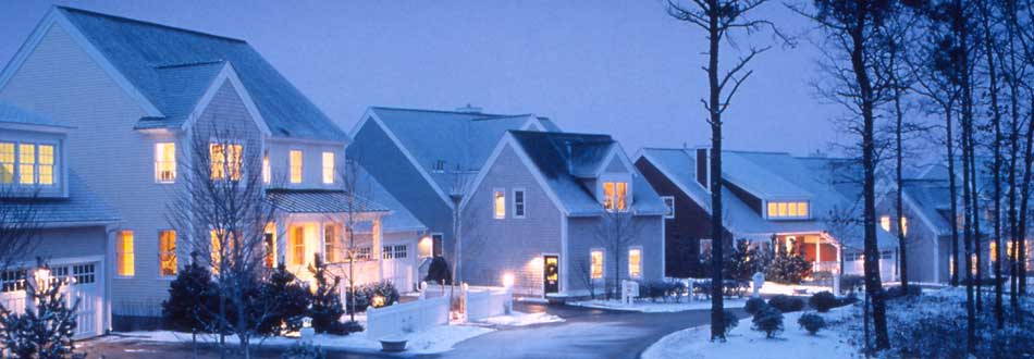 Snow-covered neighborhood at dusk with every window lit