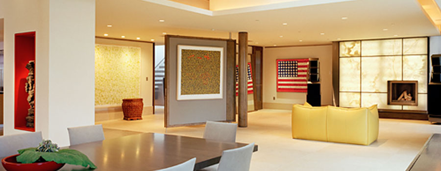 Open living and dining room with recessed ceiling lights and a backlit stone fireplace wall