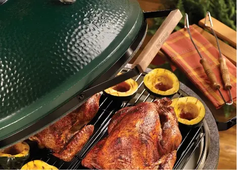 Large green ceramic grill with a whole chicken and squash cooking on the grate